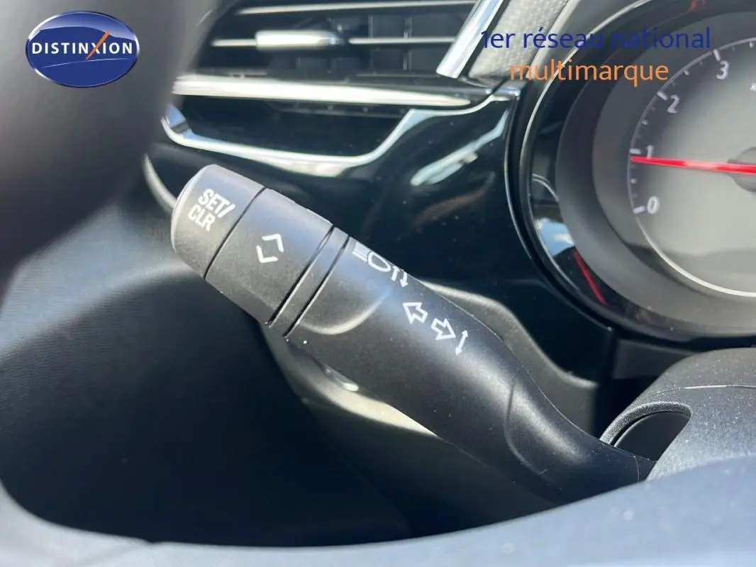 Gros plan sur la commande de clignotant noire dans l’habitacle de l’Opel Corsa gris, tableau de bord partiellement visible.