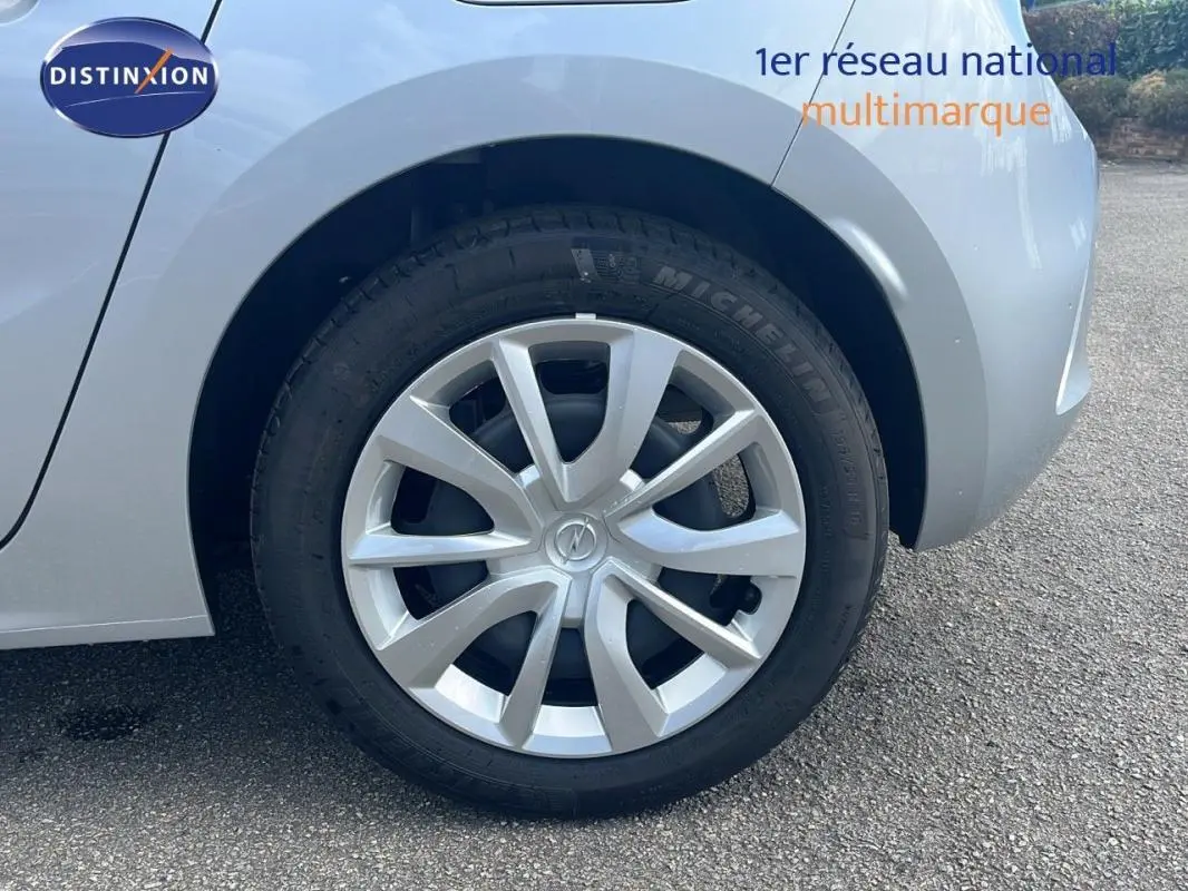 Gros plan sur la roue avant droite grise d'une Opel Corsa 2025 avec jante alu et logo Opel au centre.