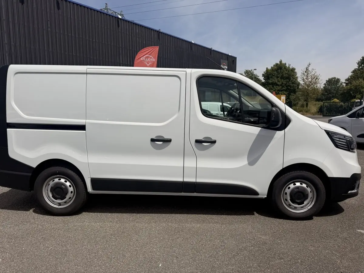 Renault Trafic Fourgon blanc vu de profil côté droit, avec portes latérales pleines et jantes acier grises.