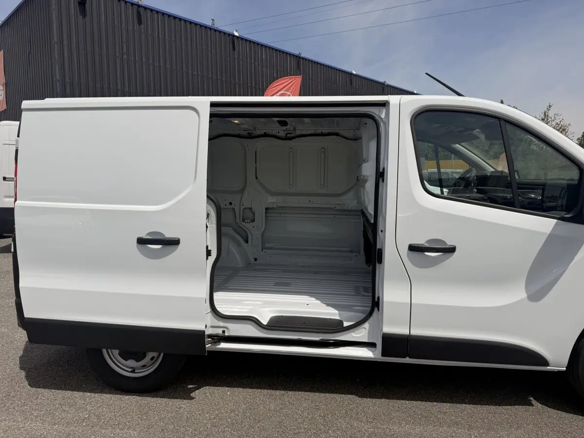 Vue latérale droite du Renault Trafic Fourgon blanc 2025 avec porte coulissante ouverte montrant l’espace de chargement vide.