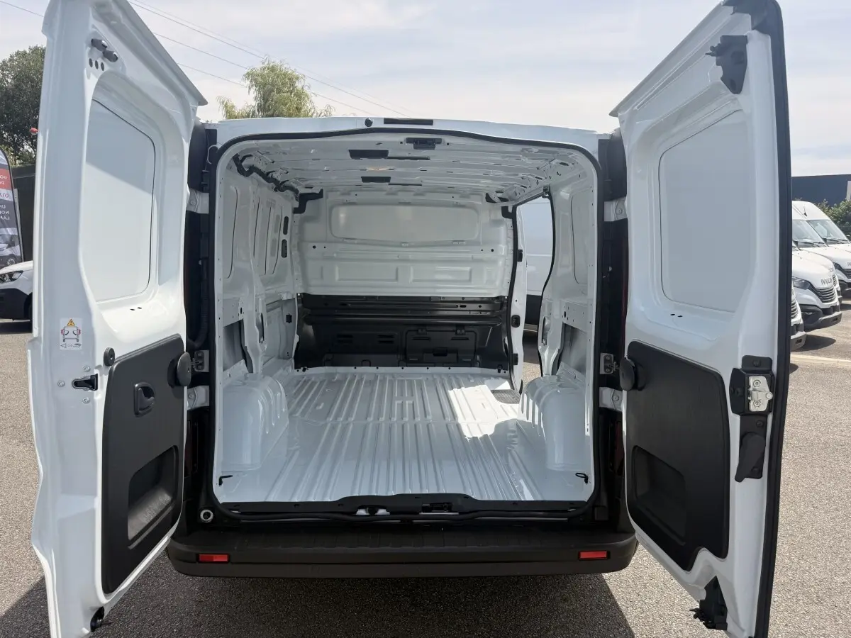 Vue arrière du Renault Trafic Fourgon blanc 2025 avec portes ouvertes montrant l'espace de chargement vide et spacieux.