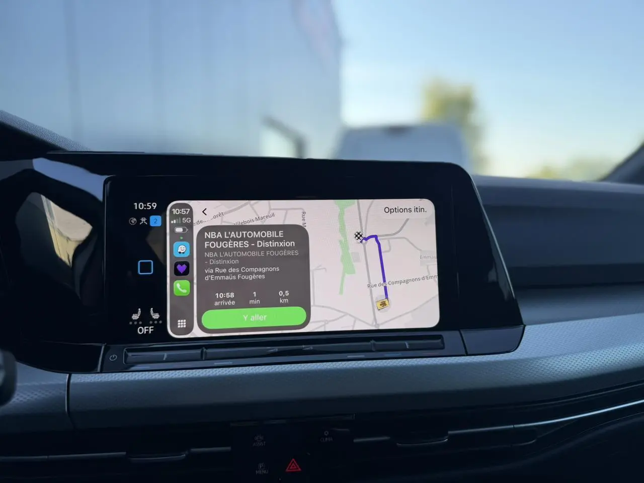 Écran tactile central de la Volkswagen Golf 8 blanche affichant la navigation GPS avec interface smartphone connectée.