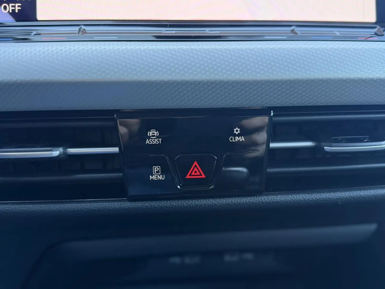 Gros plan sur la console centrale de la Volkswagen Golf 8 blanche, avec boutons d'alerte et climatisation visibles.