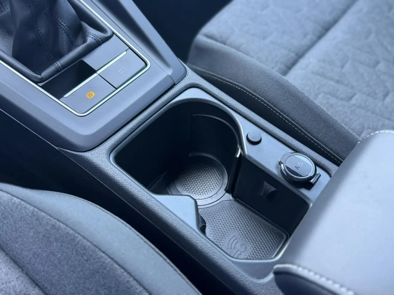 Gros plan sur la console centrale intérieure de la Volkswagen Golf 8 blanche, avec prise 12V et espace de rangement.