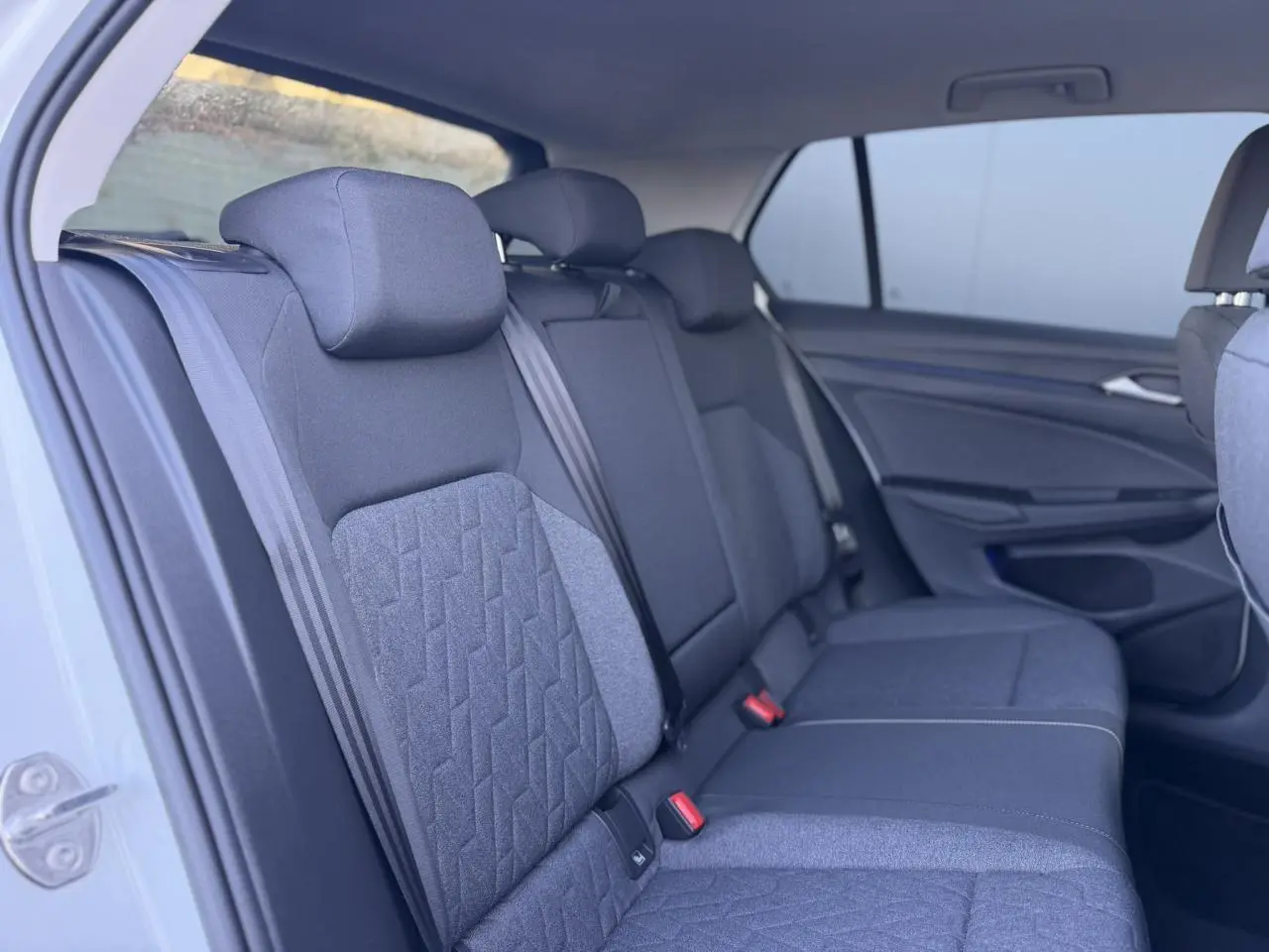 Vue intérieure côté gauche des sièges arrière en tissu gris de la Volkswagen Golf 8 blanche.