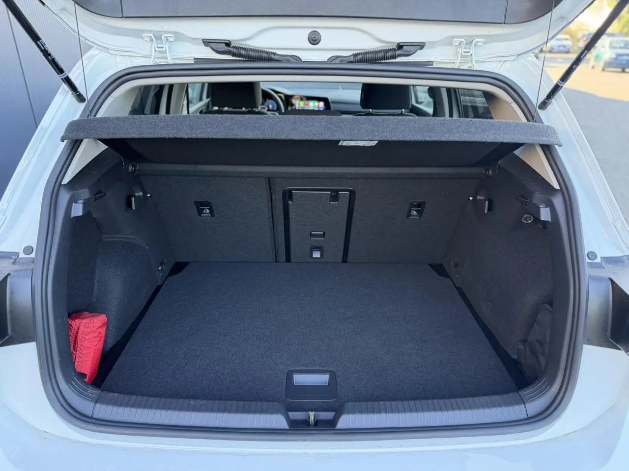 Coffre ouvert vu de l'arrière d'une Volkswagen Golf 8 blanche, montrant un espace de chargement propre et spacieux.