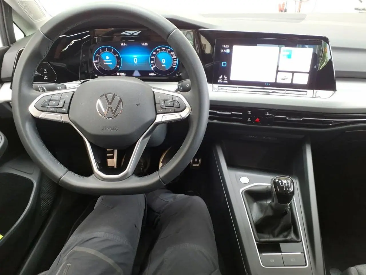 Vue intérieure centrée sur le volant multifonction et la console avec levier de vitesse manuelle d'une Volkswagen Golf 8 blanche.