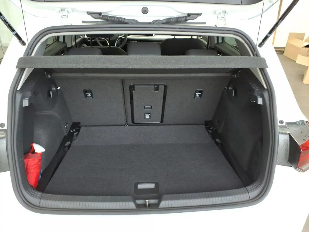 Coffre ouvert vu de l'arrière d'une Volkswagen Golf 8 blanche, montrant un espace de chargement propre et spacieux.