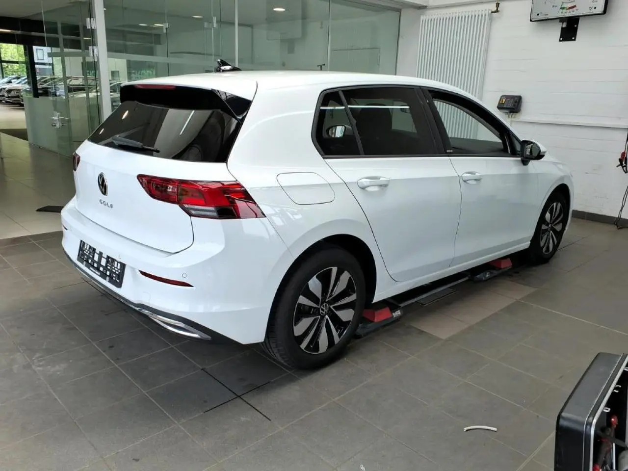 Volkswagen Golf 8 blanche vue 3/4 arrière droit en intérieur avec jantes alliage et vitres teintées.