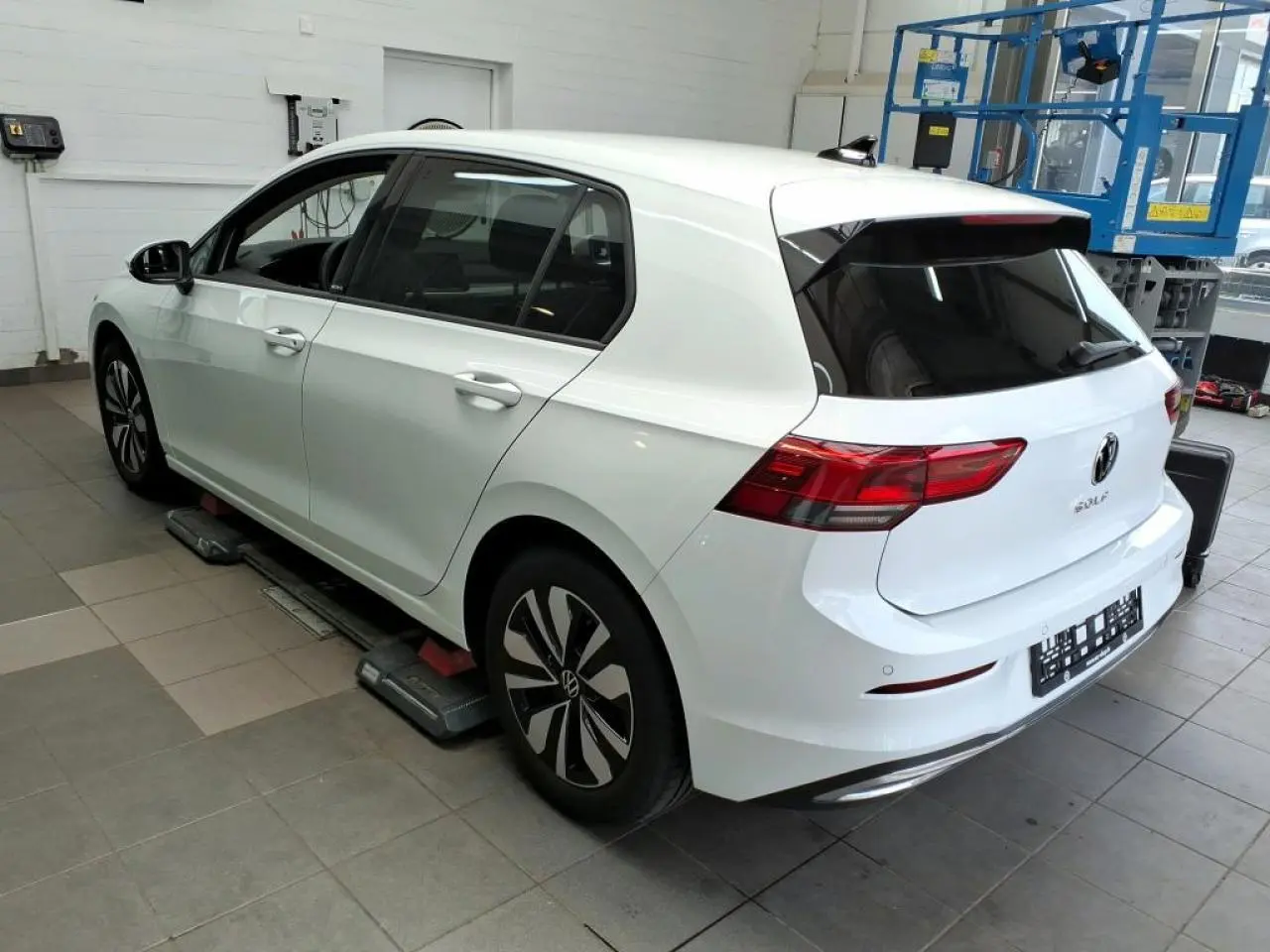 Vue 3/4 arrière droite d'une Volkswagen Golf 8 blanche Pure avec feux arrière LED et jantes alliage Norfolk.