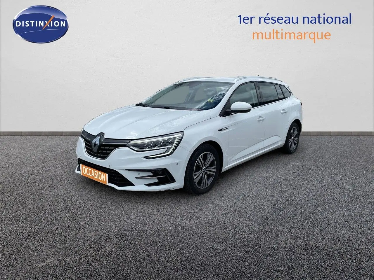 Renault Mégane Break blanc glacier en 3/4 avant droit, avec calandre noire et feux LED distinctifs.