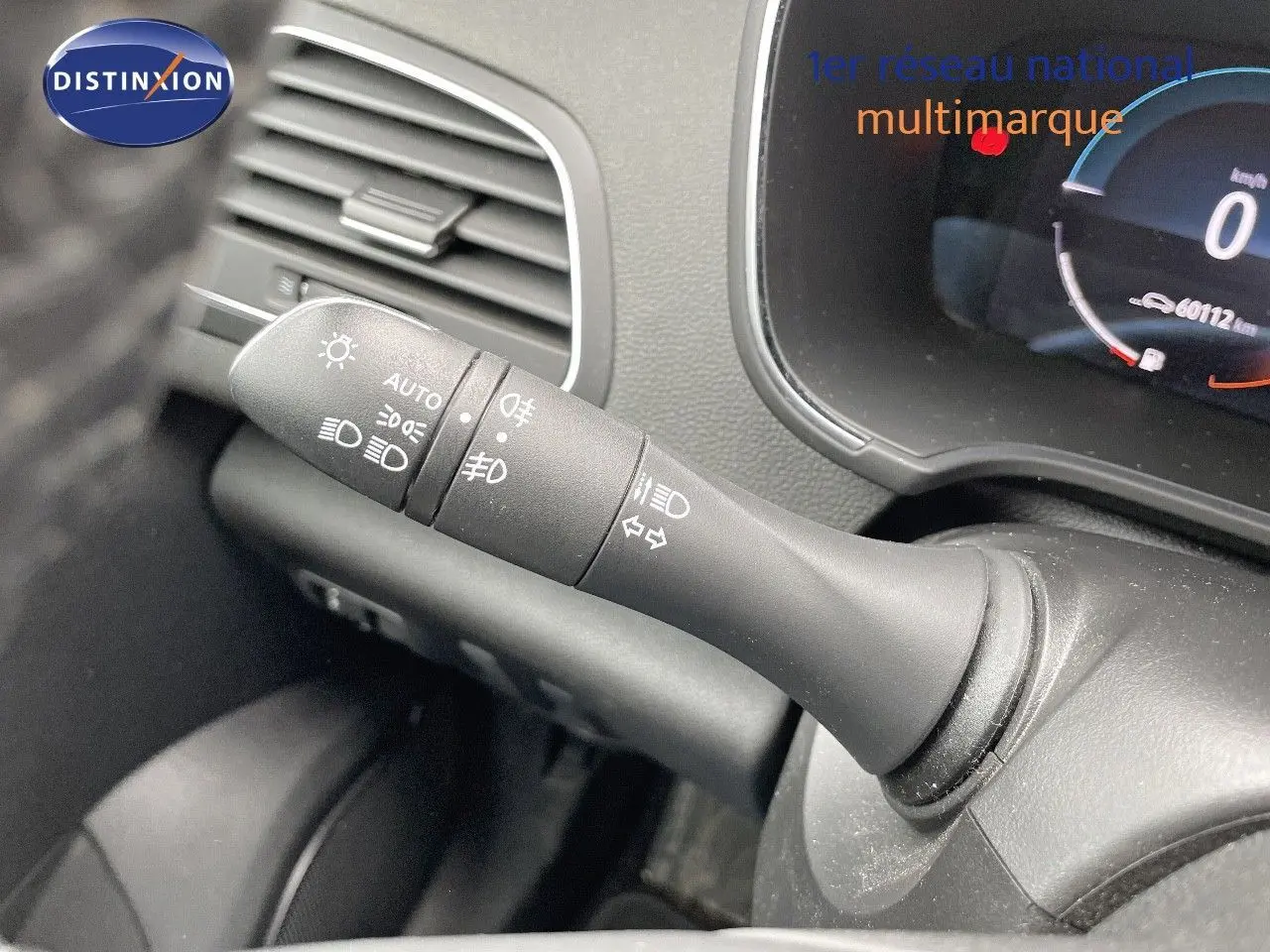 Gros plan sur la commande des phares à gauche du volant dans l’habitacle d’une Renault Mégane Break blanc glacier.