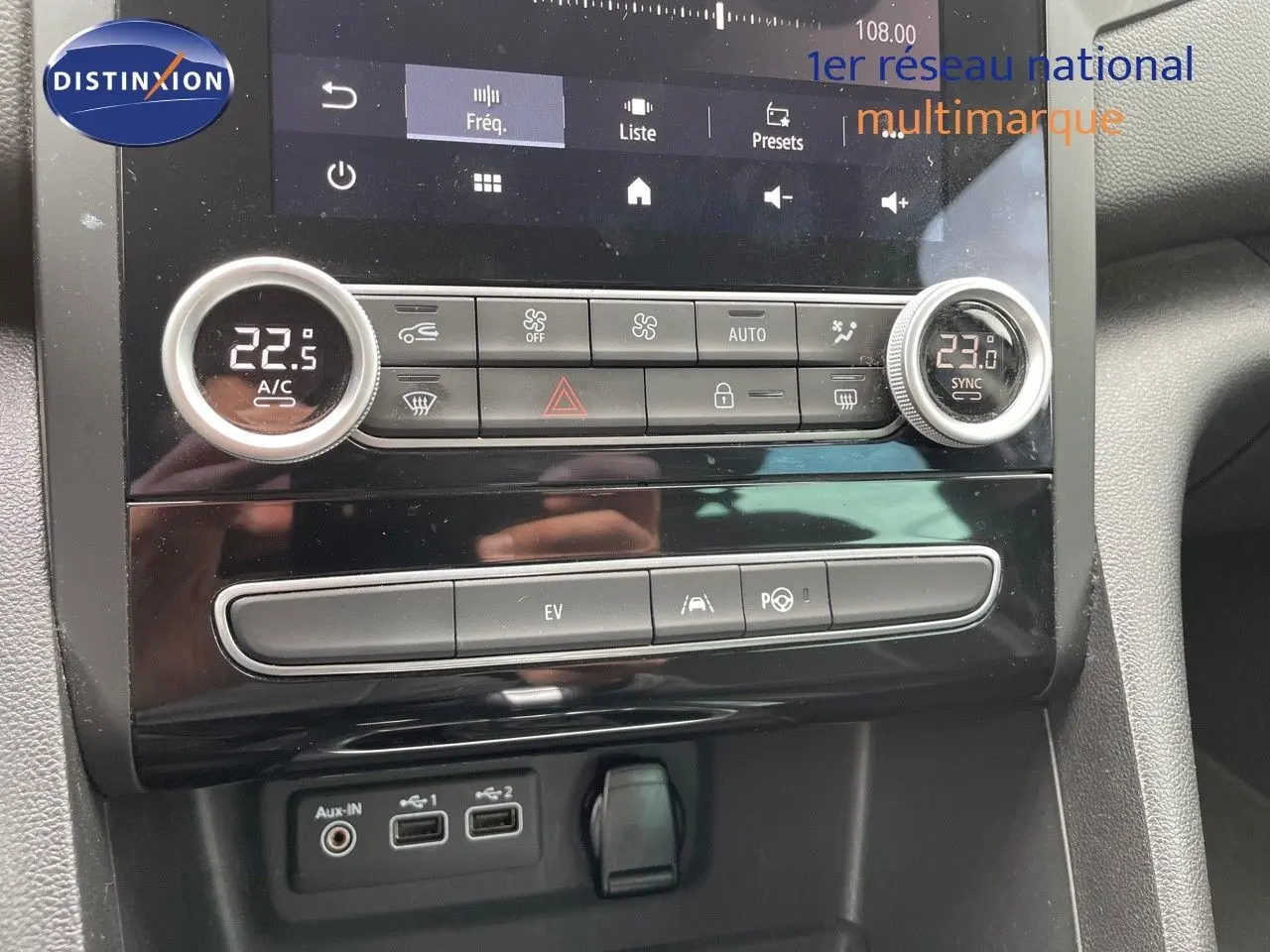 Vue intérieure centrée sur la console centrale de la Renault Mégane Break blanche, avec commandes climatisation et écran tactile.