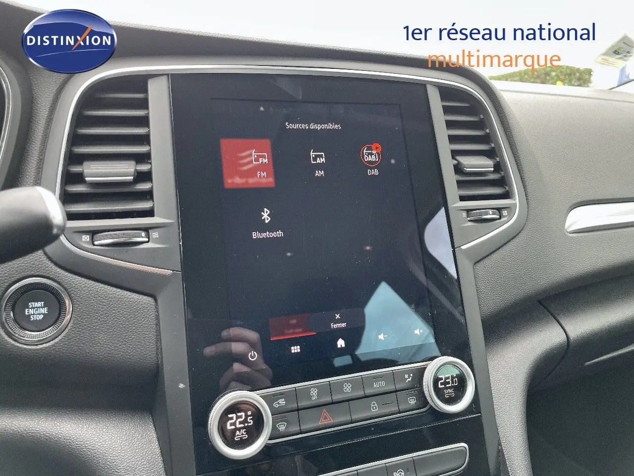 Vue intérieure centrée sur l’écran tactile et la console centrale d’une Renault Mégane Break blanc glacier, version hybride rechargeable.