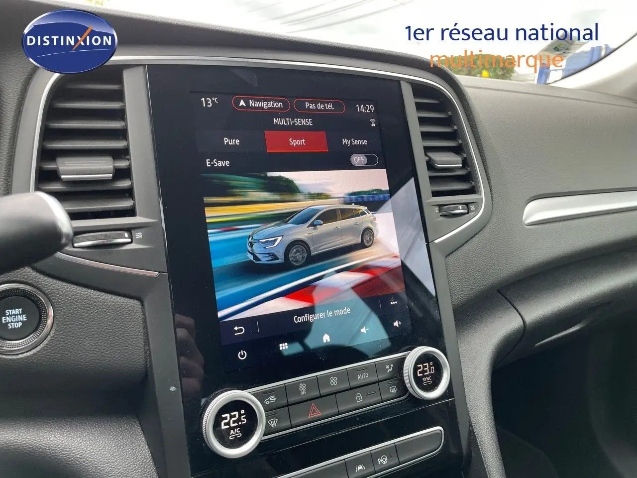 Vue intérieure centrée sur l'écran tactile du tableau de bord affichant une Renault Mégane Break blanc glacier en mode sport.