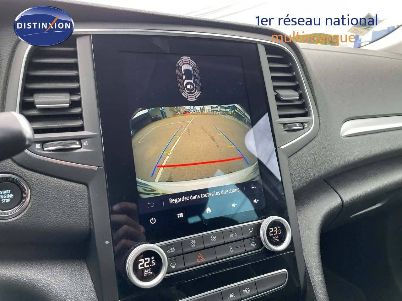 Vue intérieure du tableau de bord de la Renault Mégane Break blanc glacier, avec écran tactile affichant la caméra de recul.