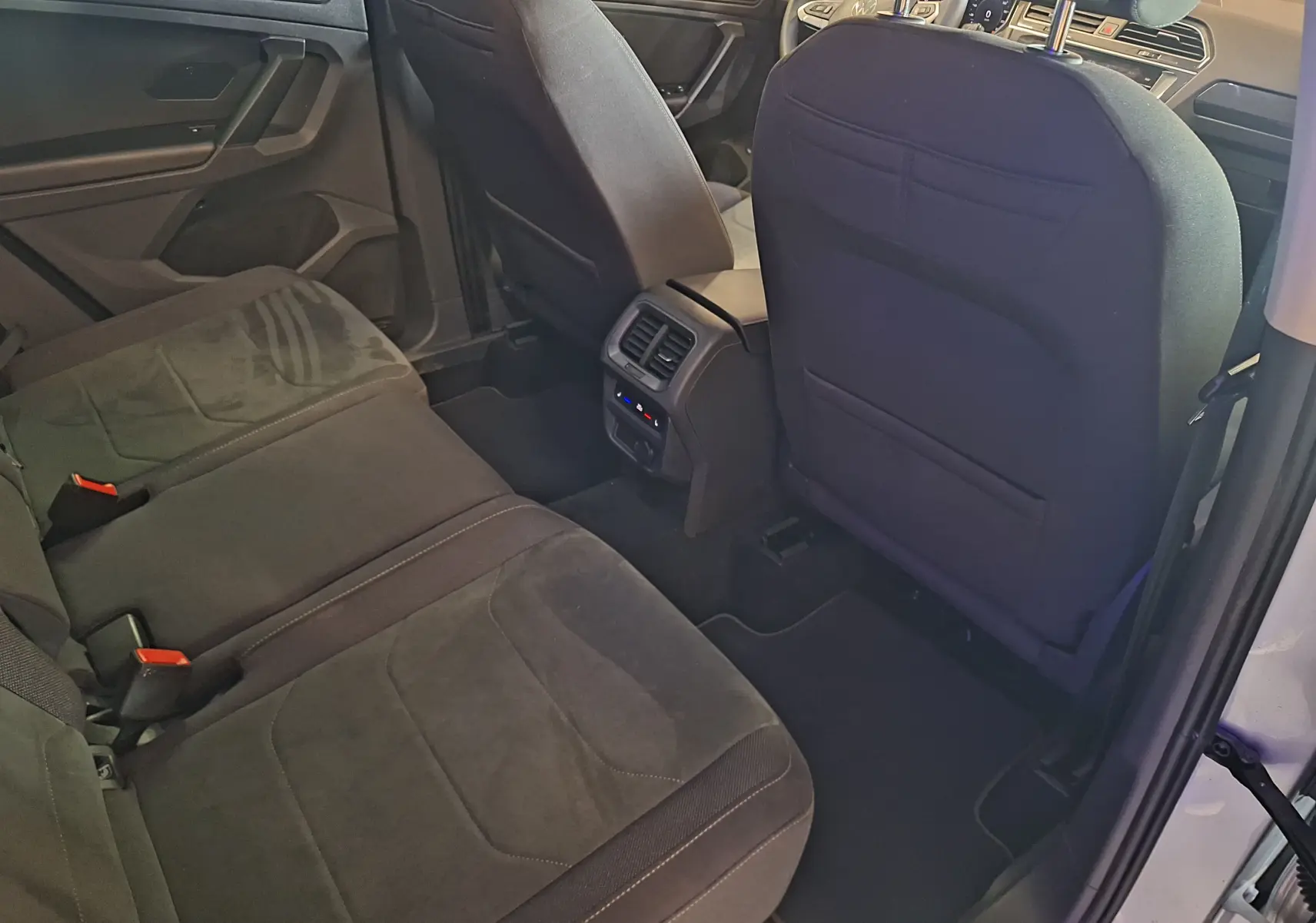Intérieur arrière du Volkswagen Tiguan gris, vue côté droit montrant les sièges Microfleece et la console centrale avec aérateurs.