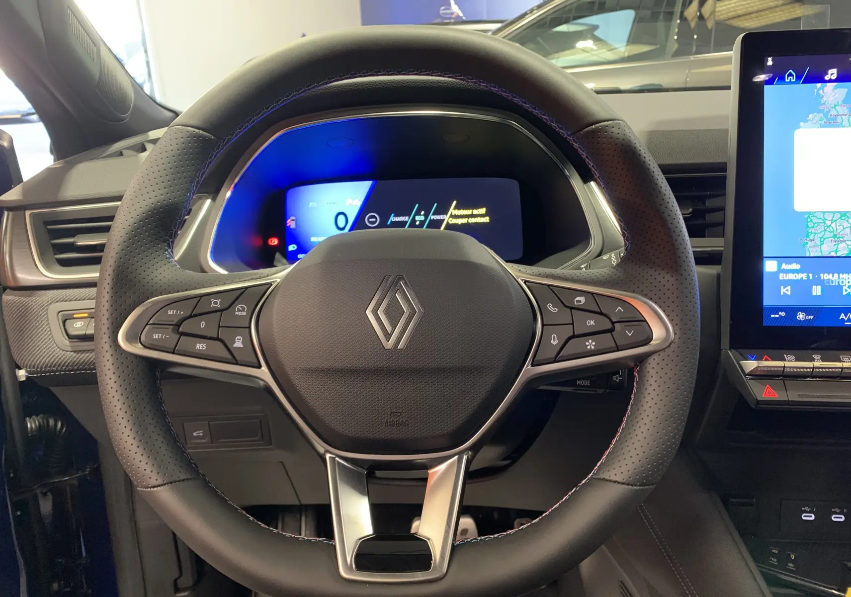 Volant en cuir perforé avec surpiqûres tricolores du Renault Symbioz E-Tech 2025, tableau de bord numérique et écran tactile visible.