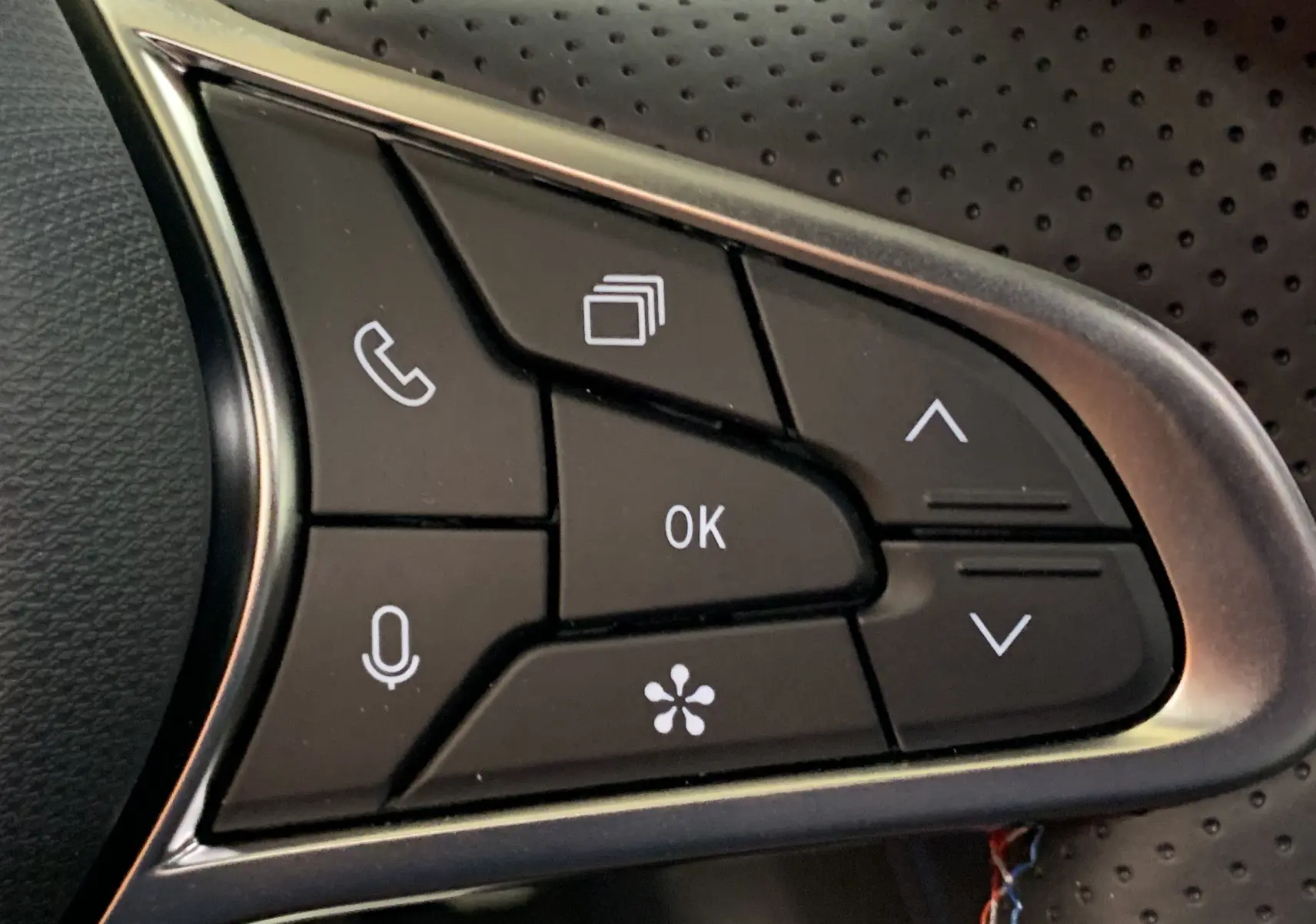 Gros plan sur les commandes multifonctions noires du volant perforé du Renault Symbioz E-Tech Full Hybrid 2025.