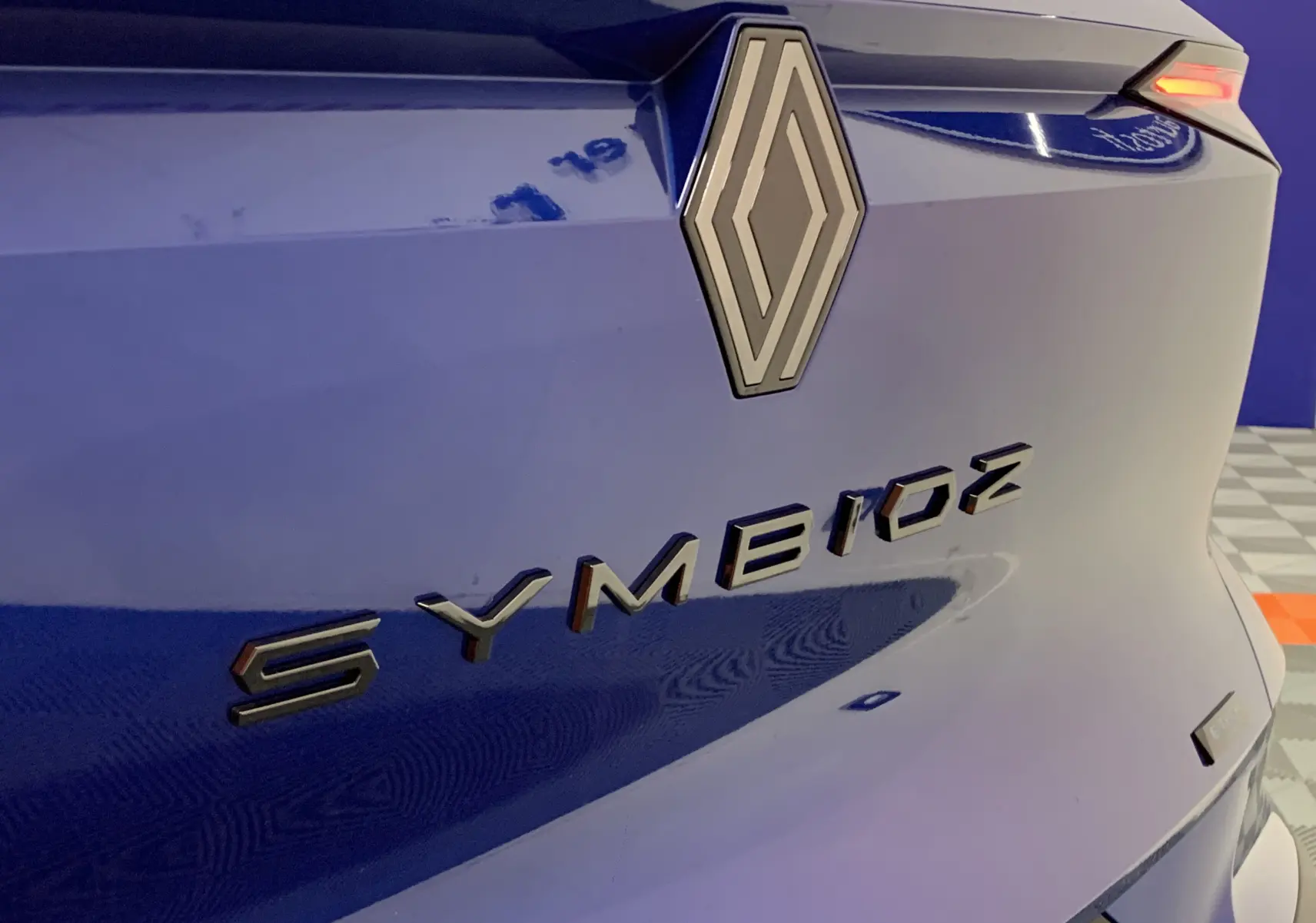 Gros plan sur l'arrière bleu iron du Renault Symbioz avec logo et badge E-TECH visible en angle latéral droit.