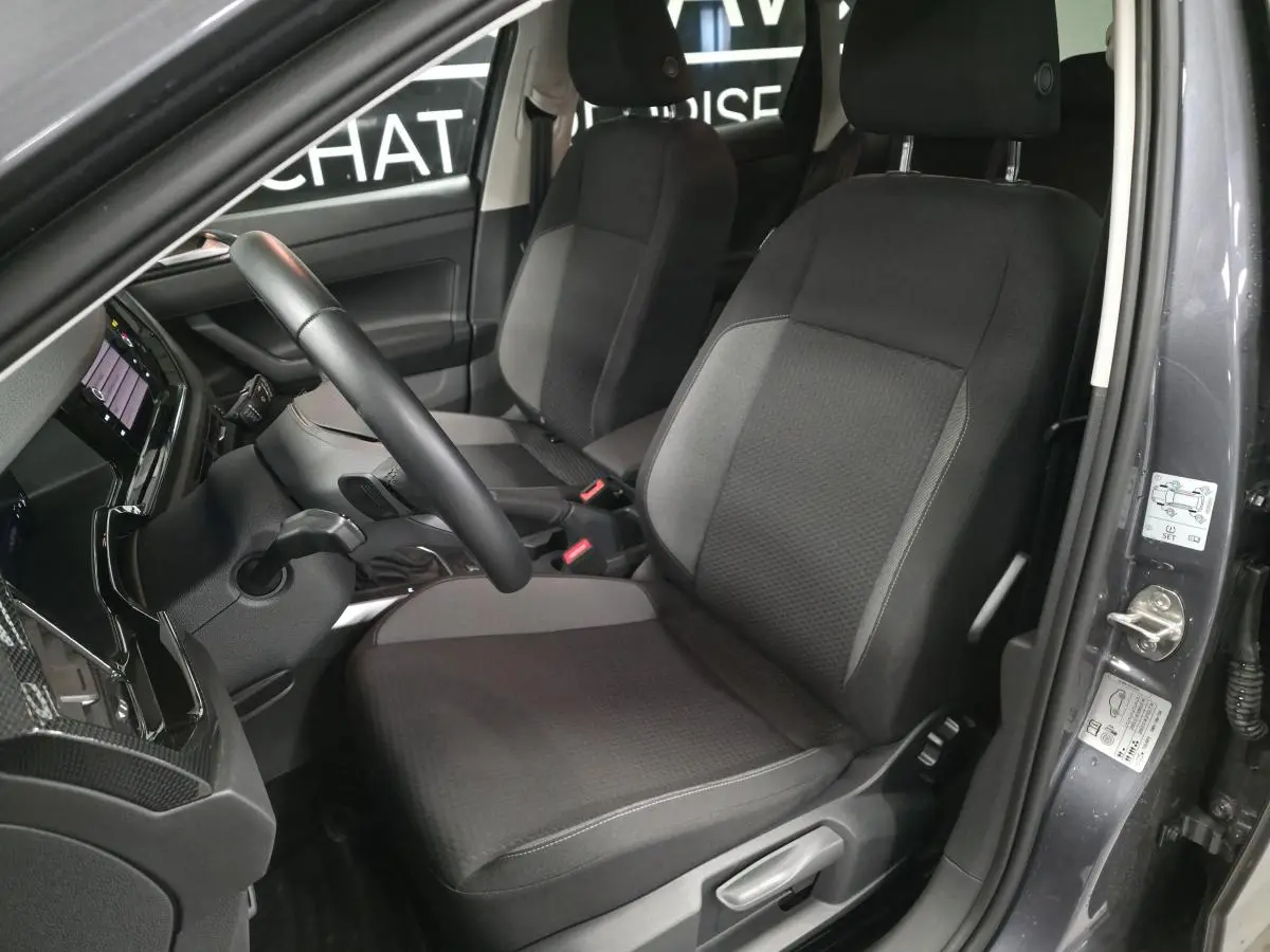 Vue intérieure côté conducteur de la Volkswagen Polo gris, avec sièges tissu noir et volant multifonction cuir.