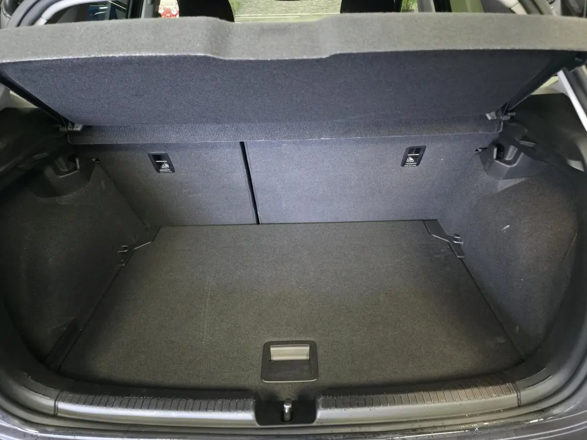 Coffre ouvert vu de l'arrière d'une Volkswagen Polo gris, montrant l'espace de chargement et la banquette arrière rabattable.