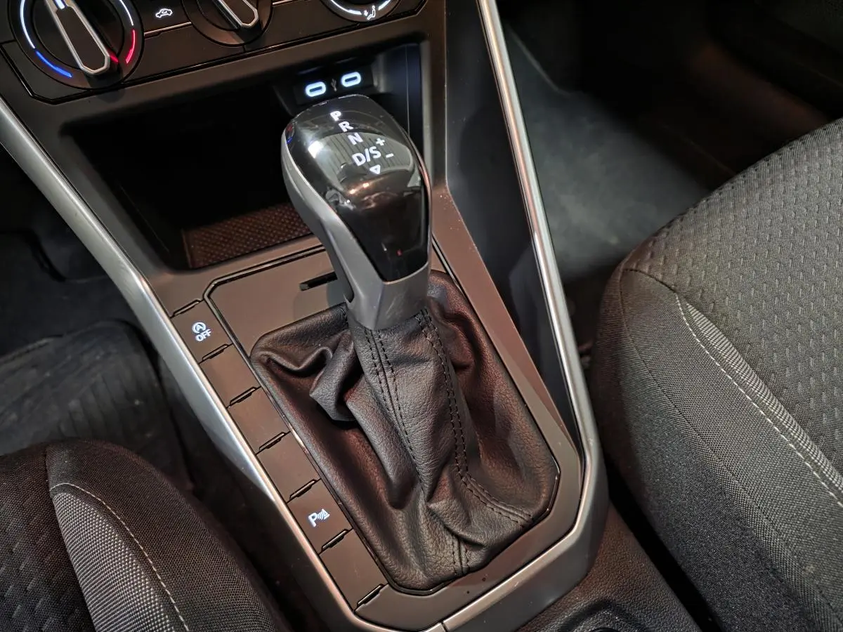 Gros plan sur levier de vitesses automatique noir et console centrale grise dans Volkswagen Polo gris 2025.