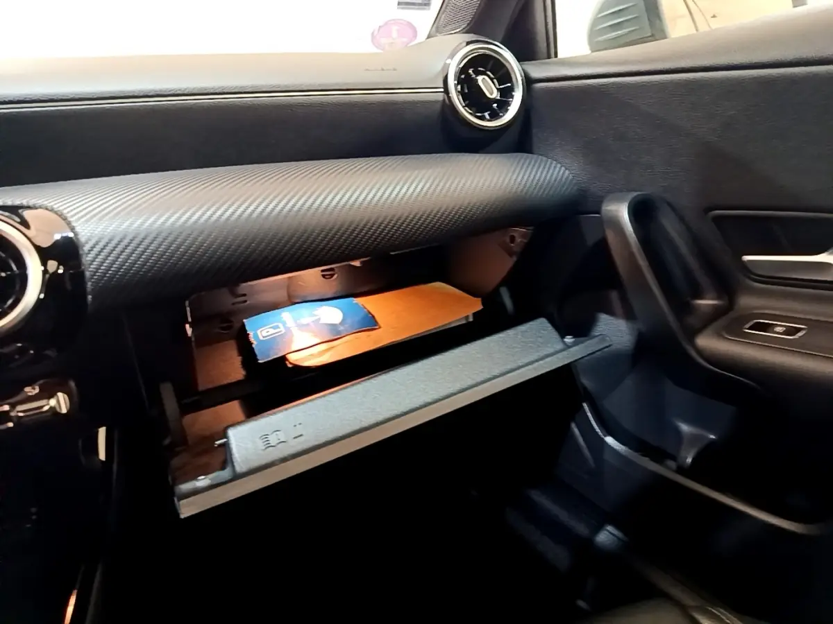 Gros plan sur la boîte à gants ouverte côté passager du Mercedes Classe A 250 e Business Line gris foncé, tableau de bord texturé.