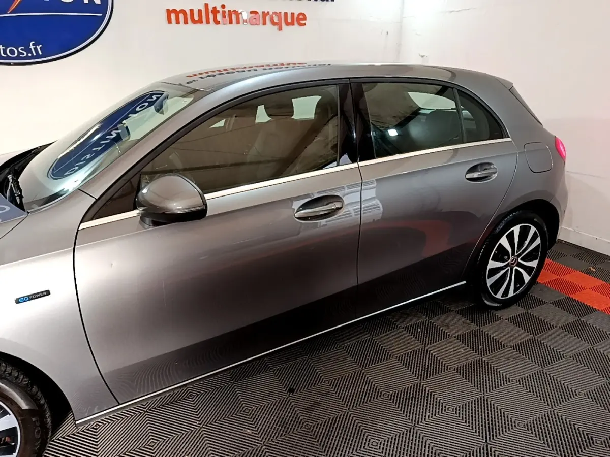 Vue latérale droite d'une Mercedes Classe A 250 e Business Line gris foncé avec jantes distinctives et logo EQ Power.