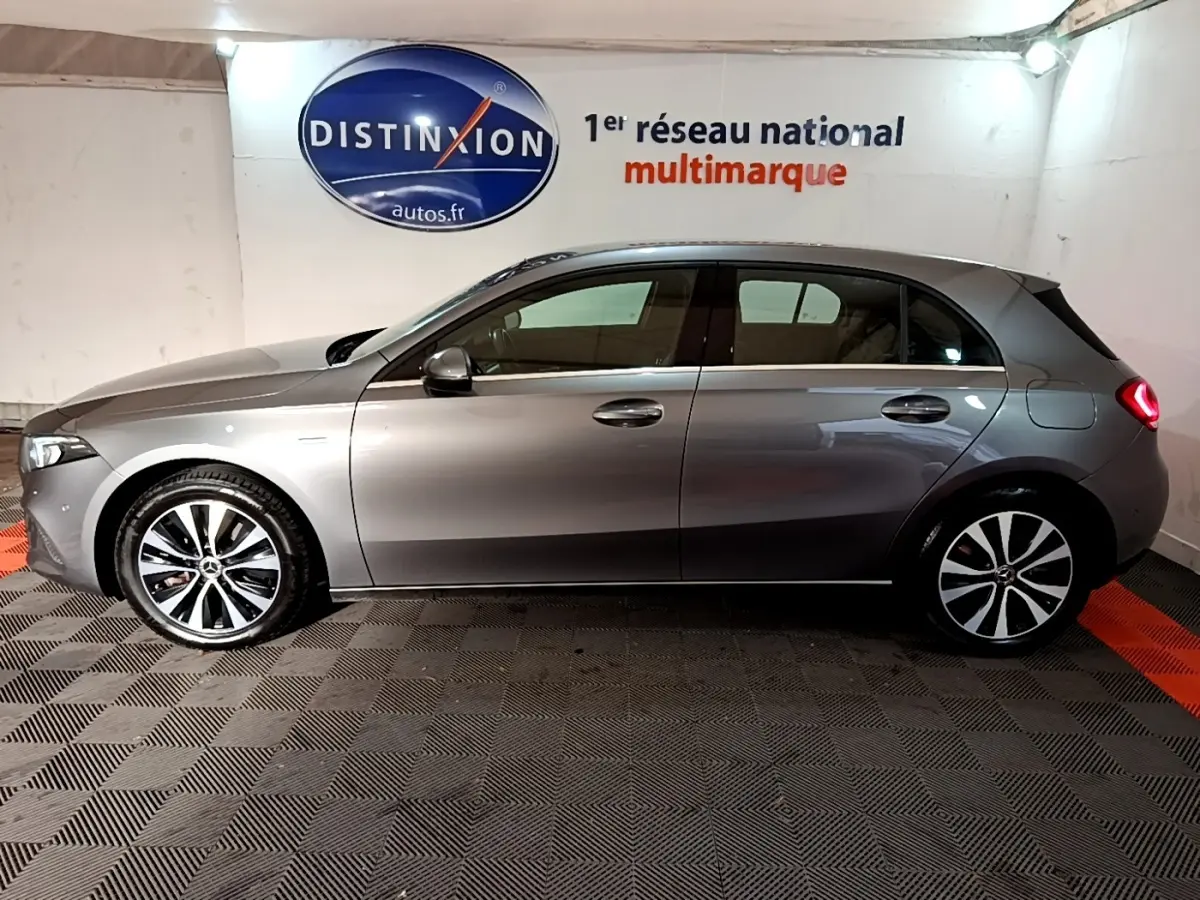 Profil côté gauche d'une Mercedes Classe A 250 e Business Line gris foncé avec jantes alliage et feux arrière allumés.