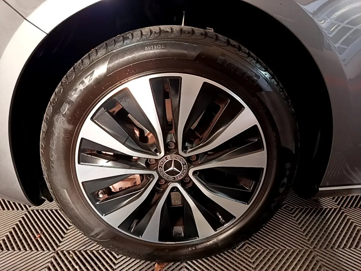 Gros plan sur la roue avant gauche d'une Mercedes Classe A gris foncé avec jante alliage bicolore au design moderne.