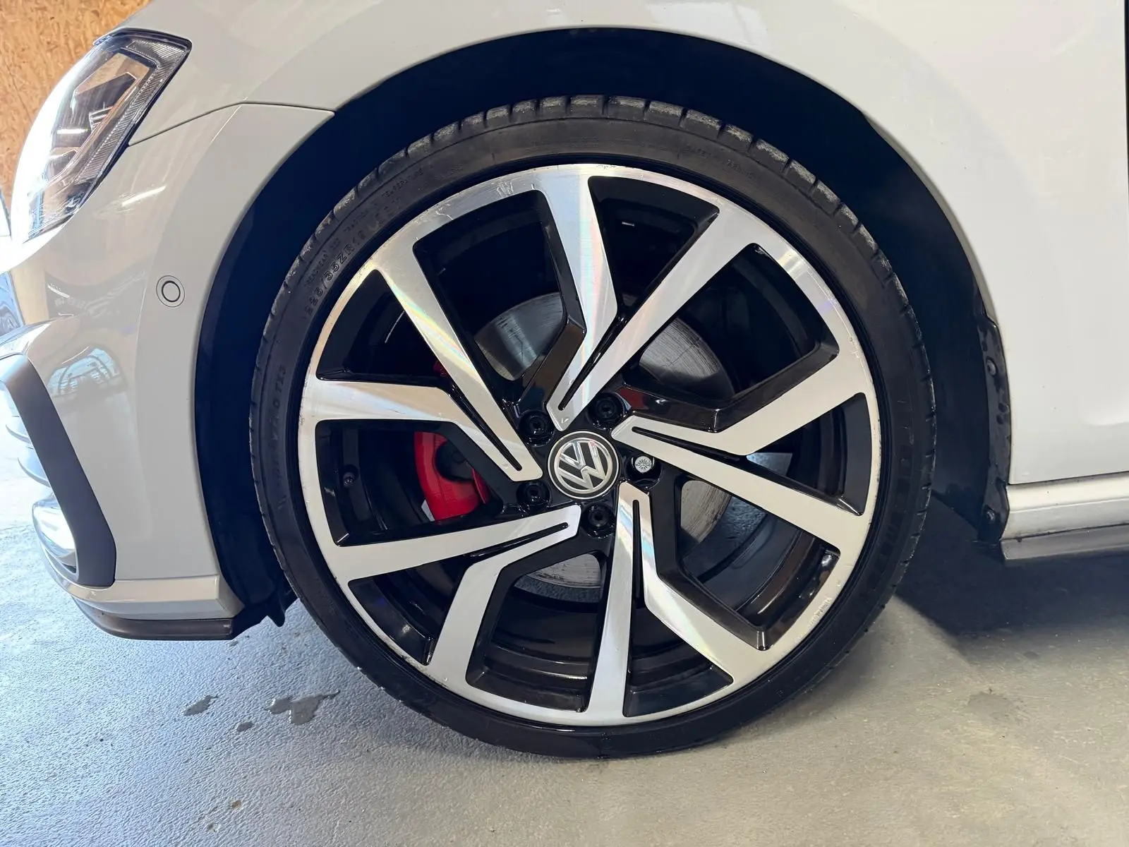 Vue intérieure côté gauche montrant les sièges sport à motif tartan et coutures rouges d'une Volkswagen Golf GTI Performance gris clair.