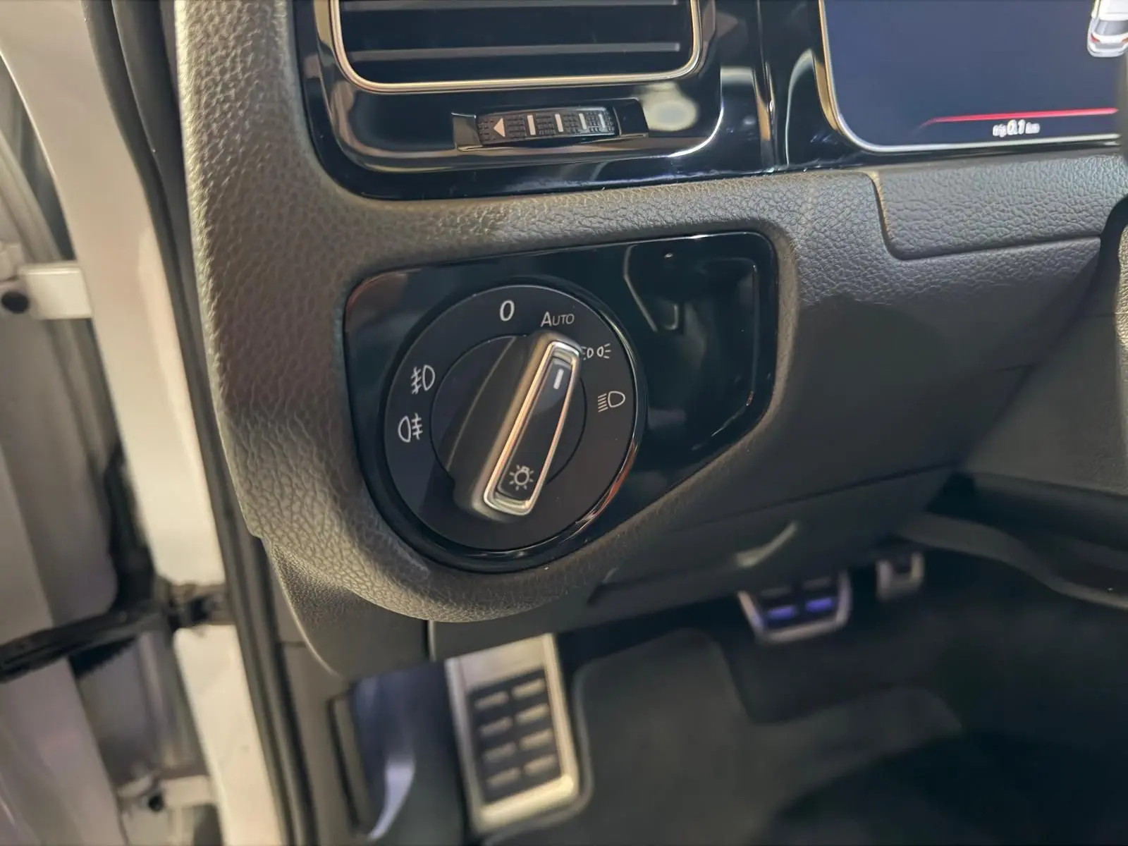 Gros plan sur le bouton de commande des phares dans l'habitacle d'une Volkswagen Golf GTI Performance gris.