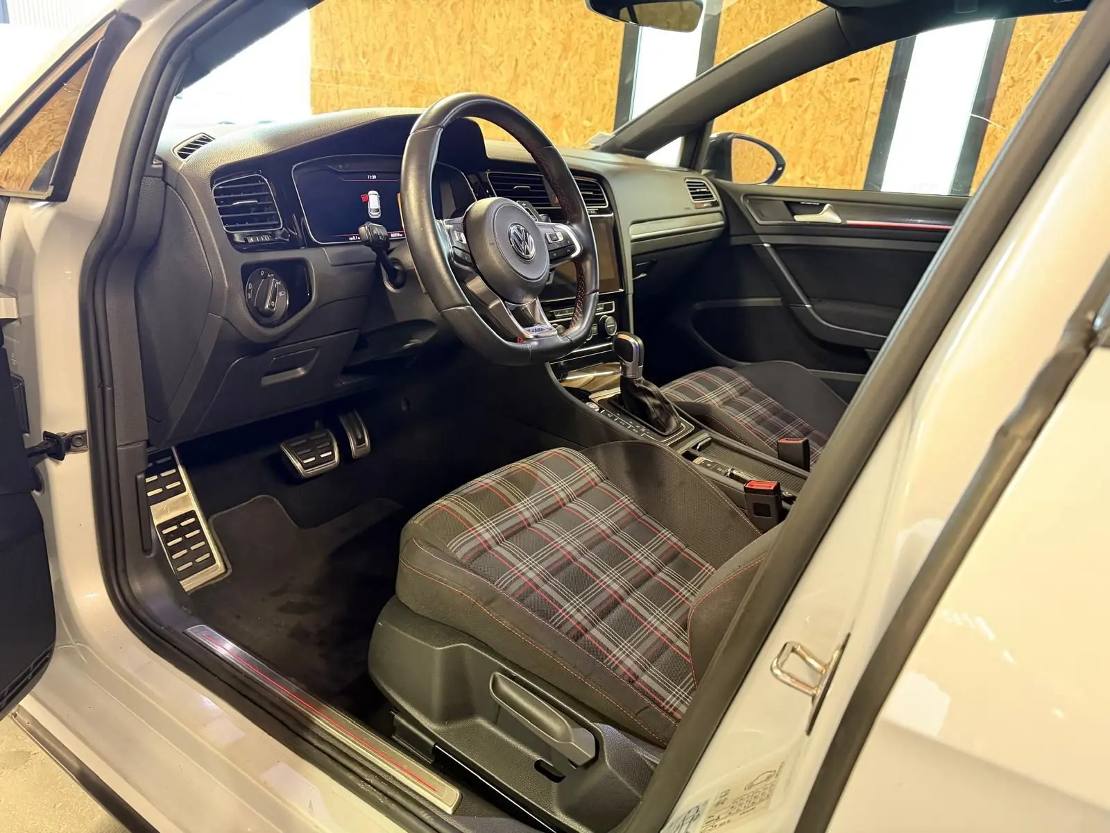 Vue intérieure centrée sur le volant sport noir avec surpiqûres rouges de la Volkswagen Golf GTI Performance gris 2018.