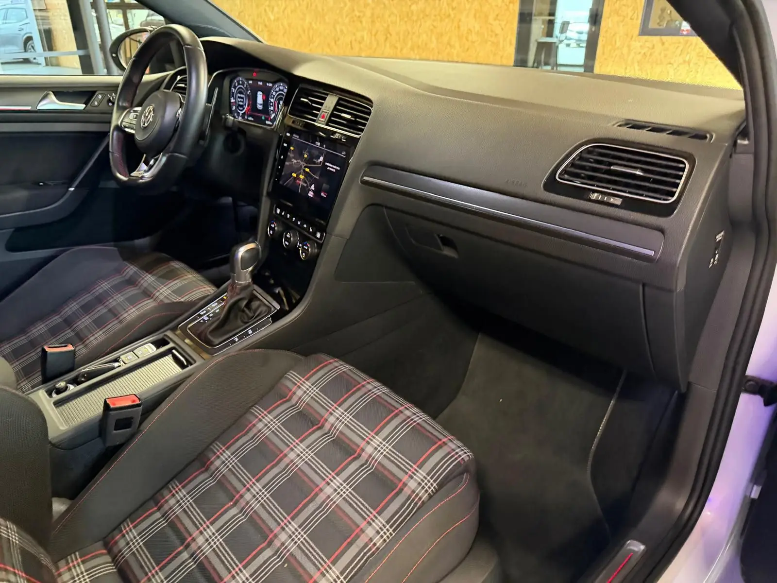 Coffre ouvert de Volkswagen Golf GTI Performance gris, vue plongeante sur le rangement sous plancher avec housses noires.