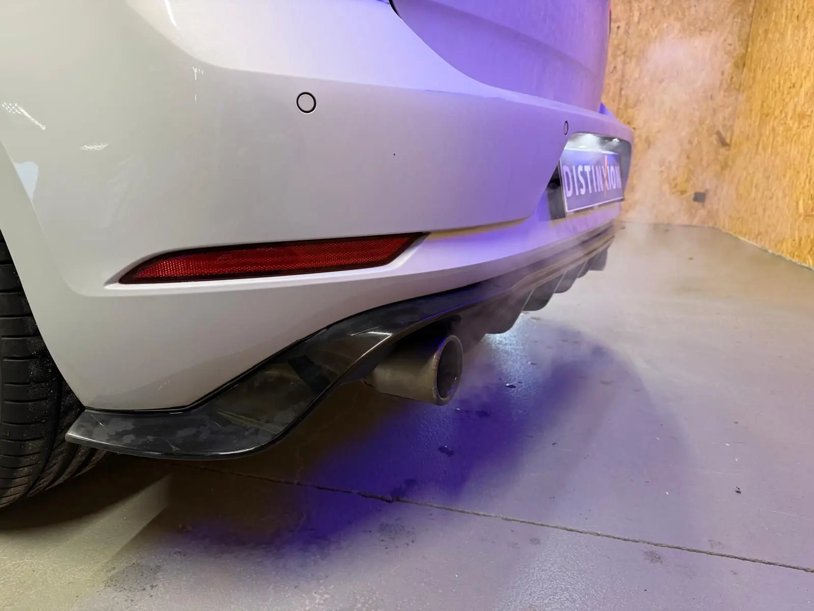 Gros plan sur l'arrière droit gris d'une Volkswagen Golf GTI Performance, avec sortie d'échappement chromée visible.