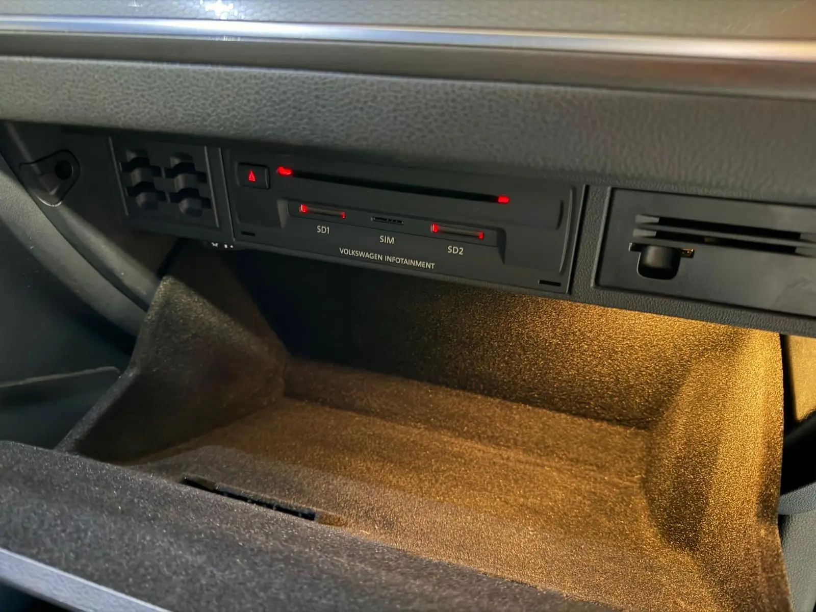 Gros plan sur la boîte à gants ouverte de la Volkswagen Golf GTI Performance 2018, intérieur noir éclairé.