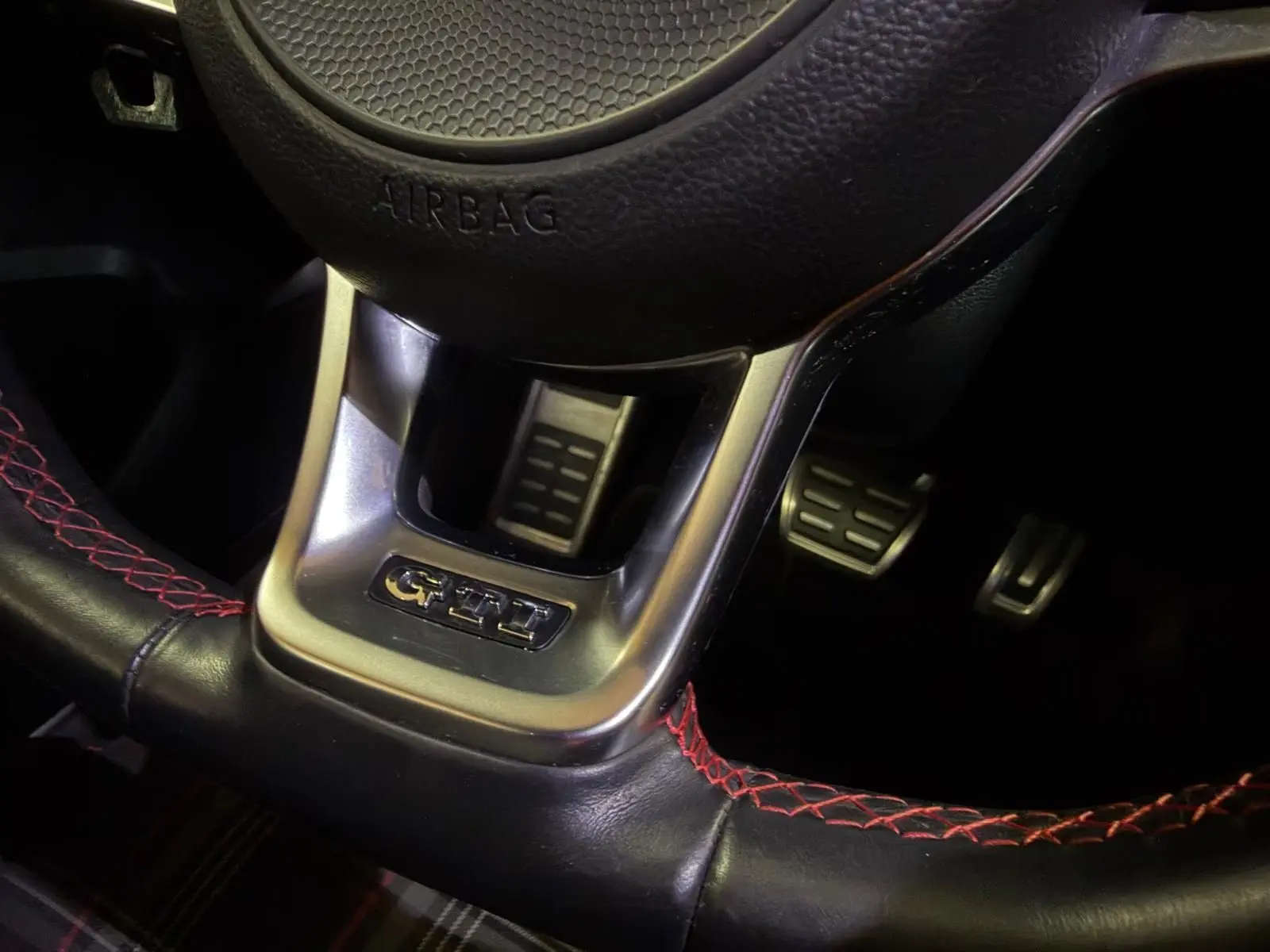 Gros plan sur le volant sport noir avec surpiqûres rouges et logo GTI d'une Volkswagen Golf GTI Performance.