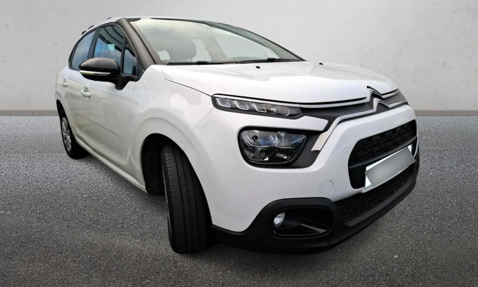 Citroën C3 blanc vue 3/4 avant droit, avec phares distinctifs et calandre noire contrastante.