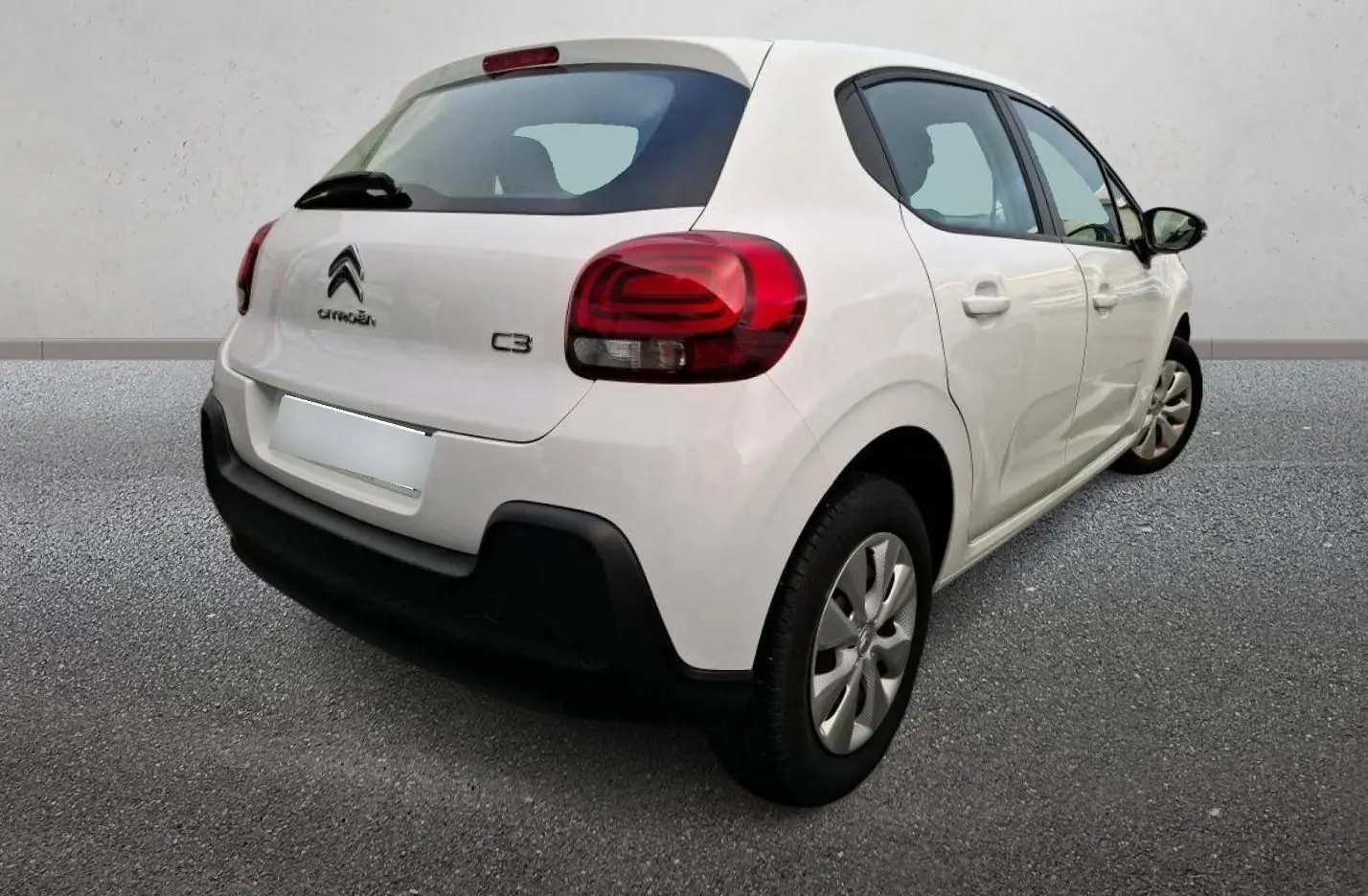 Vue 3/4 arrière droite d'une Citroën C3 blanche 2021 avec feux arrière rouges et pare-chocs noir contrastant.