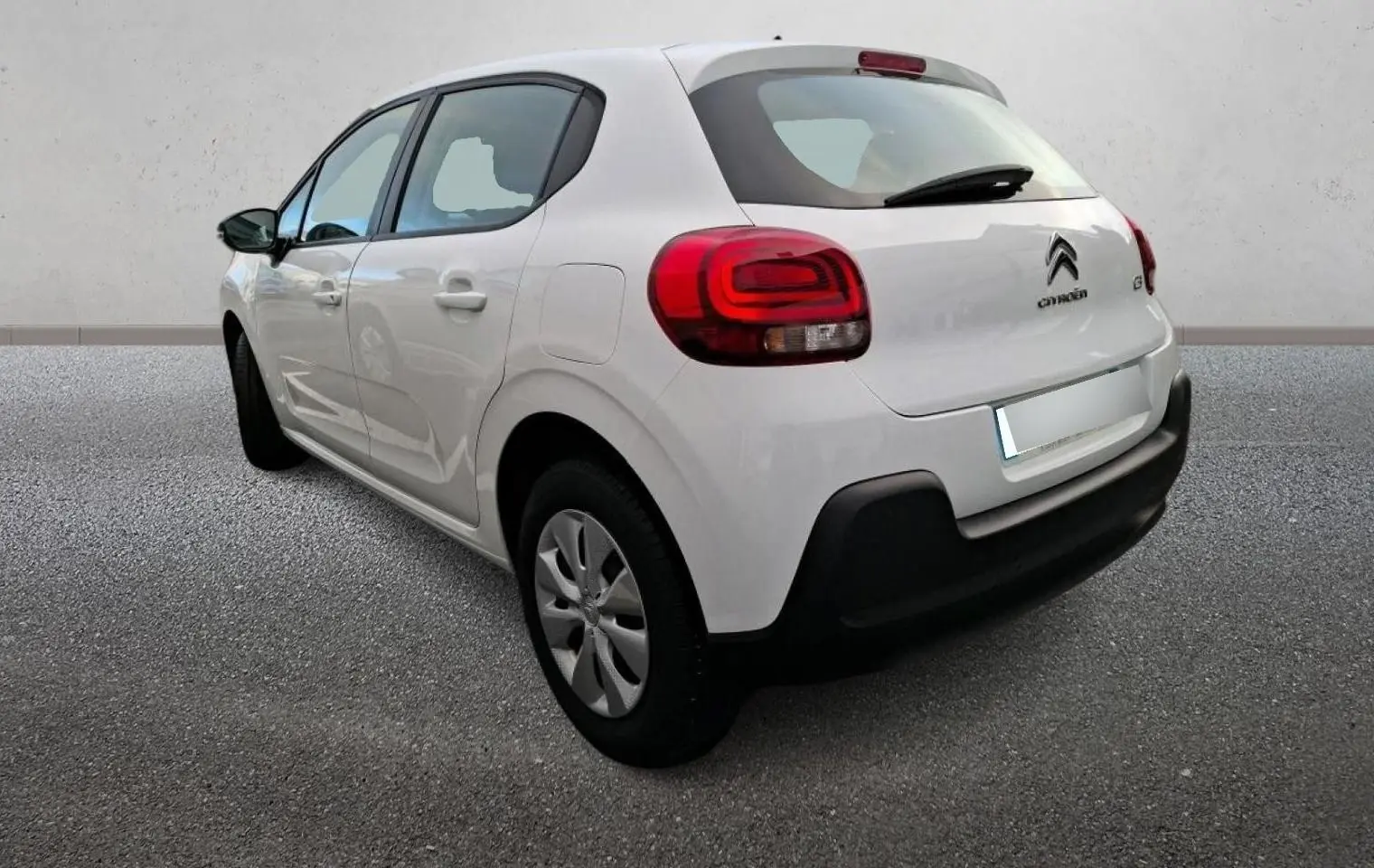 Vue 3/4 arrière droite d'une Citroën C3 blanche 2021 avec feux arrière rouges et pare-chocs noir.
