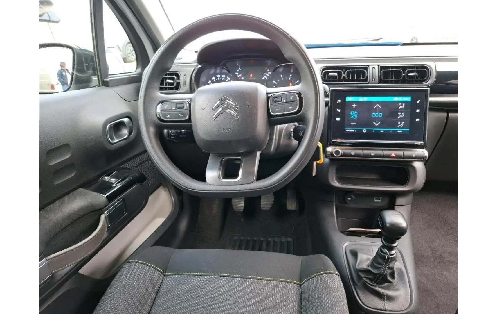 Vue intérieure centrée sur le volant et la console centrale tactile d'une Citroën C3 blanche, version 2021.