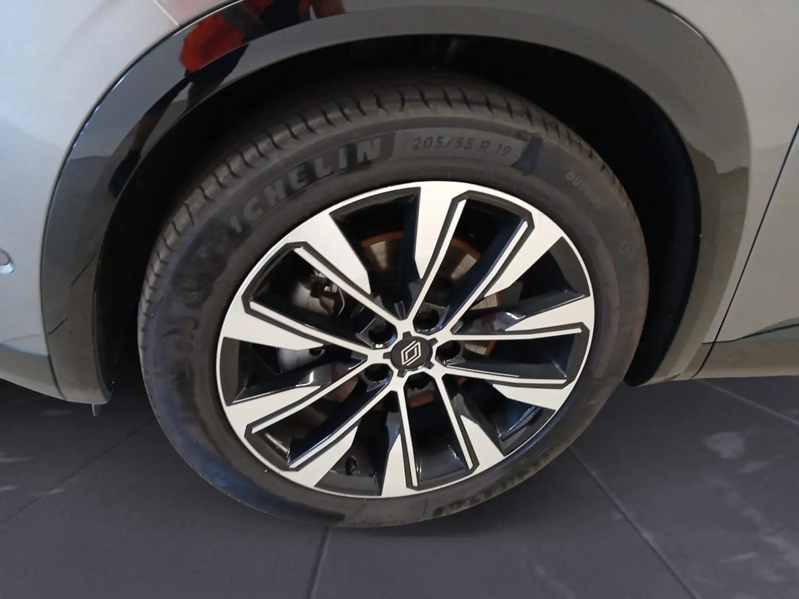 Gros plan sur la roue alliage 19'' Komah diamantée noir du côté gauche du Renault Austral gris clair.