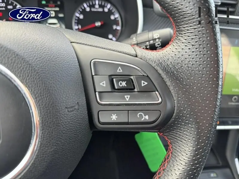 Gros plan sur les commandes multifonctions à gauche du volant cuir noir perforé avec surpiqûres rouges du MG ZS Cosmic Silver.