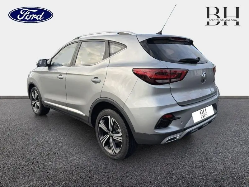 Vue 3/4 arrière droite du SUV MG ZS 2022 en Cosmic Silver métallisé avec jantes alliage et barres de toit.