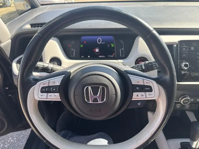 Vue rapprochée du volant cuir noir et blanc de la Honda Jazz 2021 avec tableau de bord numérique et commandes intégrées.