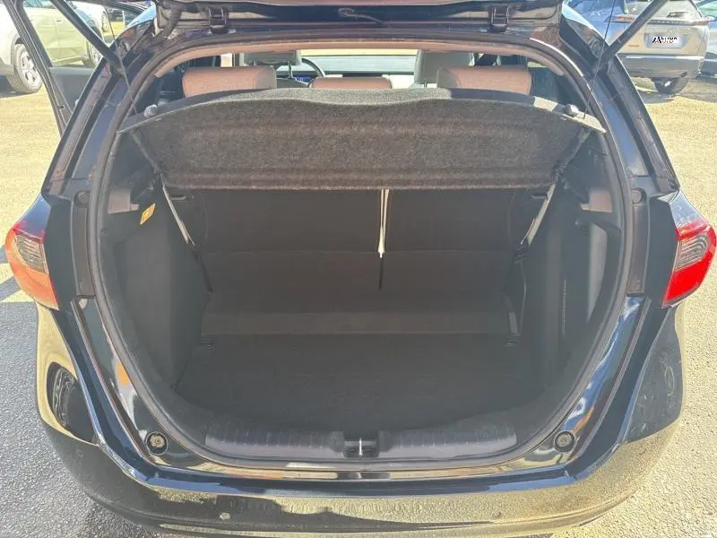Vue arrière du coffre ouvert d'une Honda Jazz 1.5 i-MMD bleu nuit nacré, montrant l'espace de chargement vide.
