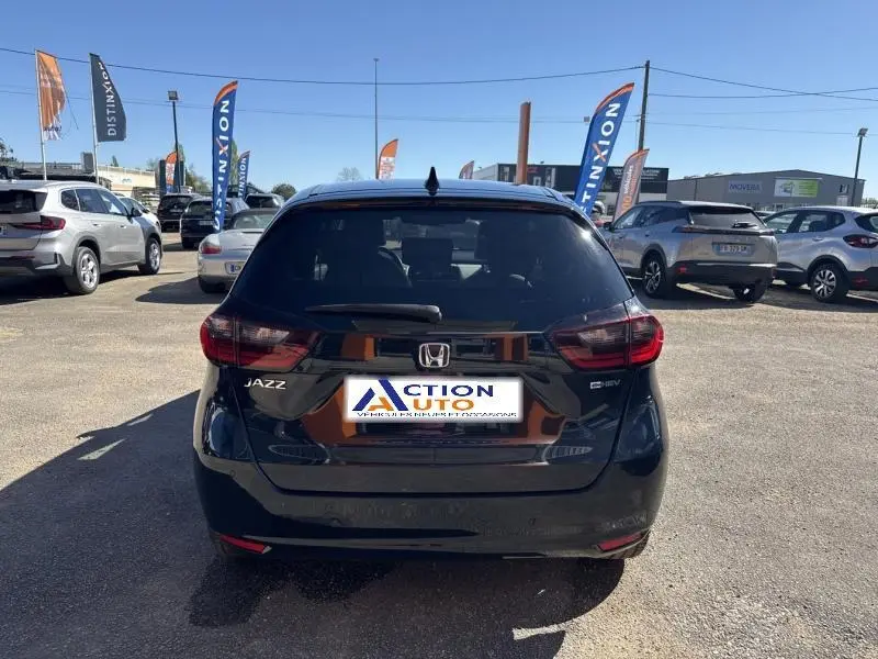 Vue arrière d'une Honda Jazz bleu nuit nacré stationnée en extérieur avec logo et badges visibles sur le hayon.