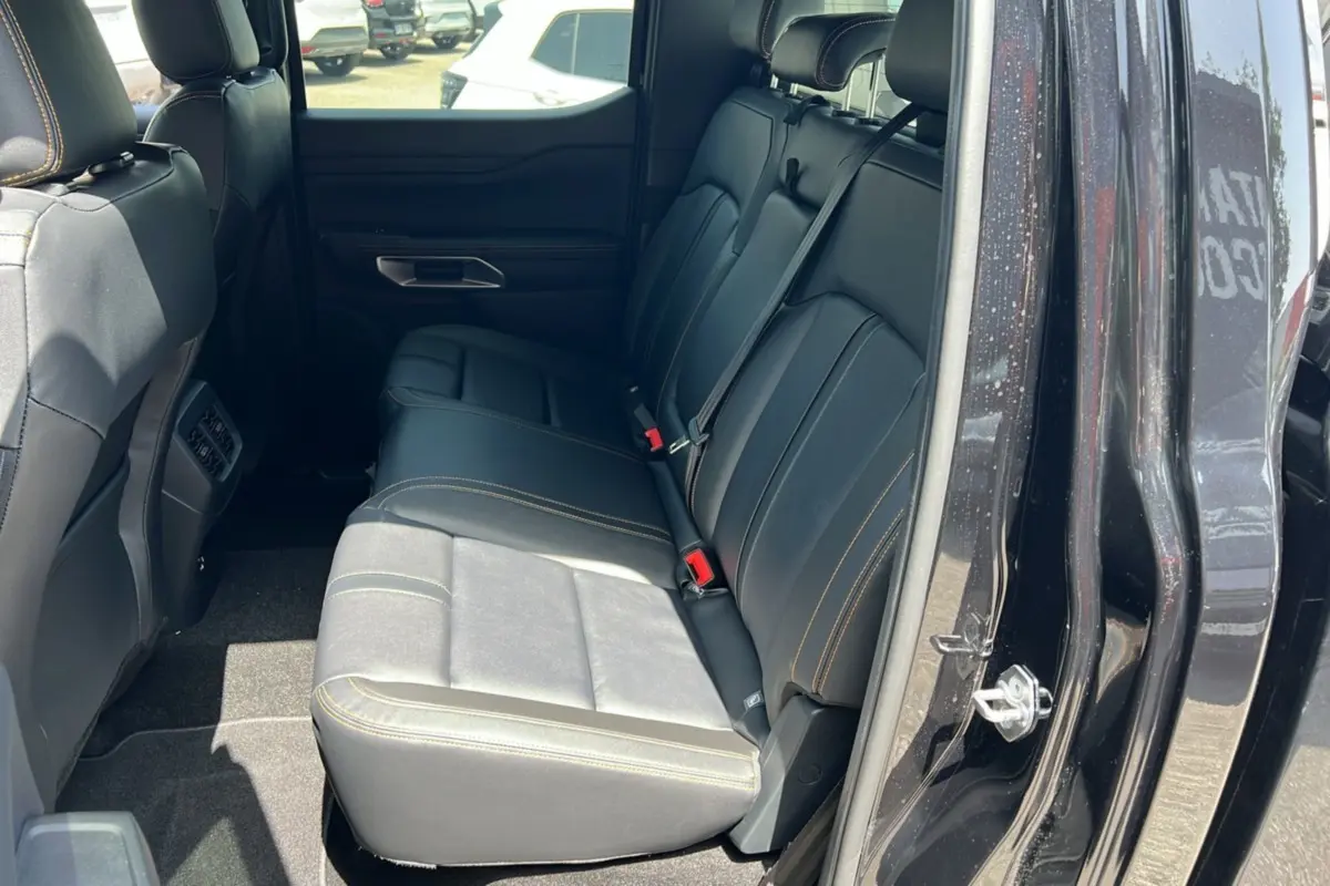 Vue intérieure côté arrière droit du Ford Ranger 2.3 PHEV Wildtrak Plus noir agate, sièges en cuir noir avec surpiqûres contrastantes.