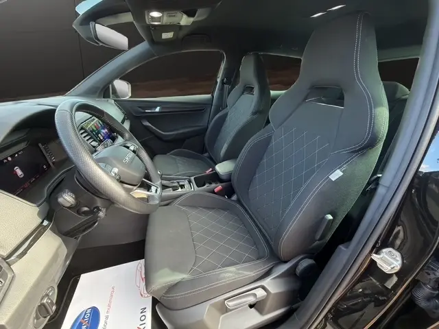 Intérieur avant droit du Skoda Karoq noir 2025, sièges sport noirs avec surpiqûres blanches et volant multifonctions.